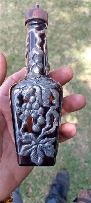 a vintage amber glass bottle encased with a sculpted pewter