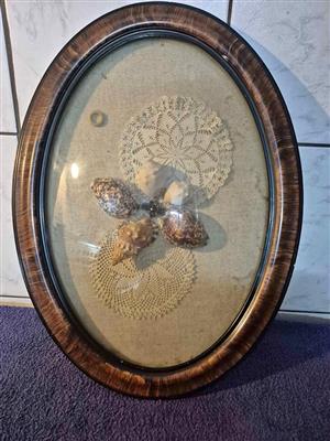 Antique oval convex picture frame featuring seashells and lace doilies.