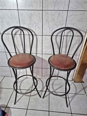 Two beautiful vintage wrought iron bar stools with round, cushioned seats.