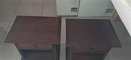 A pair of dark wood bedside pedestals featuring a single drawer and an open lower shelf.
