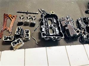 dismantled internal engine components from a BMW N20 2.0L engine, including a plastic valve cover, p