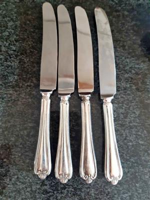Vintage set (4) of silver-plated dinner knives with detailed decorative handles.