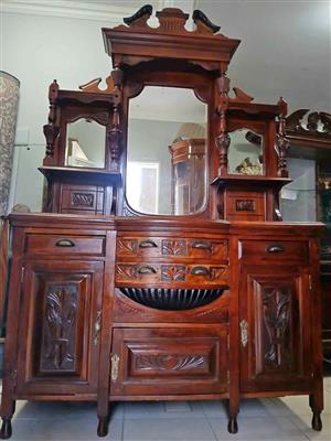 Antique Victorian‑style wooden dresser with carved details, central mirror, and side shelves.