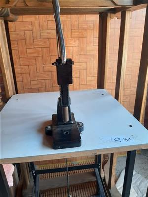 Cast-metal stud, snap or rivet press with foot linkage.