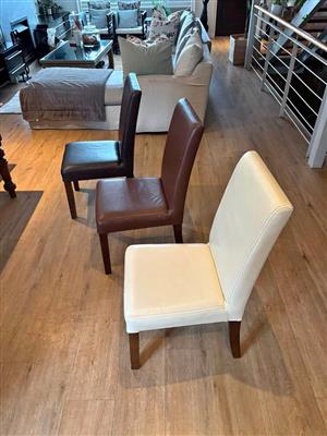 10 x leather dining chairs in various colours. They are average condition.