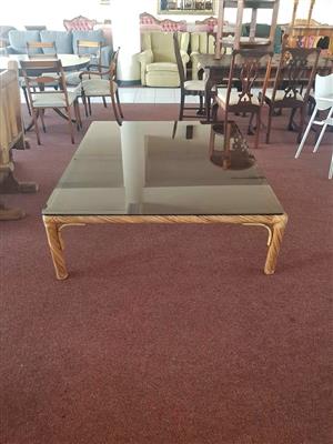 Very large coffee table features a smoked glass top set within a woven wicker